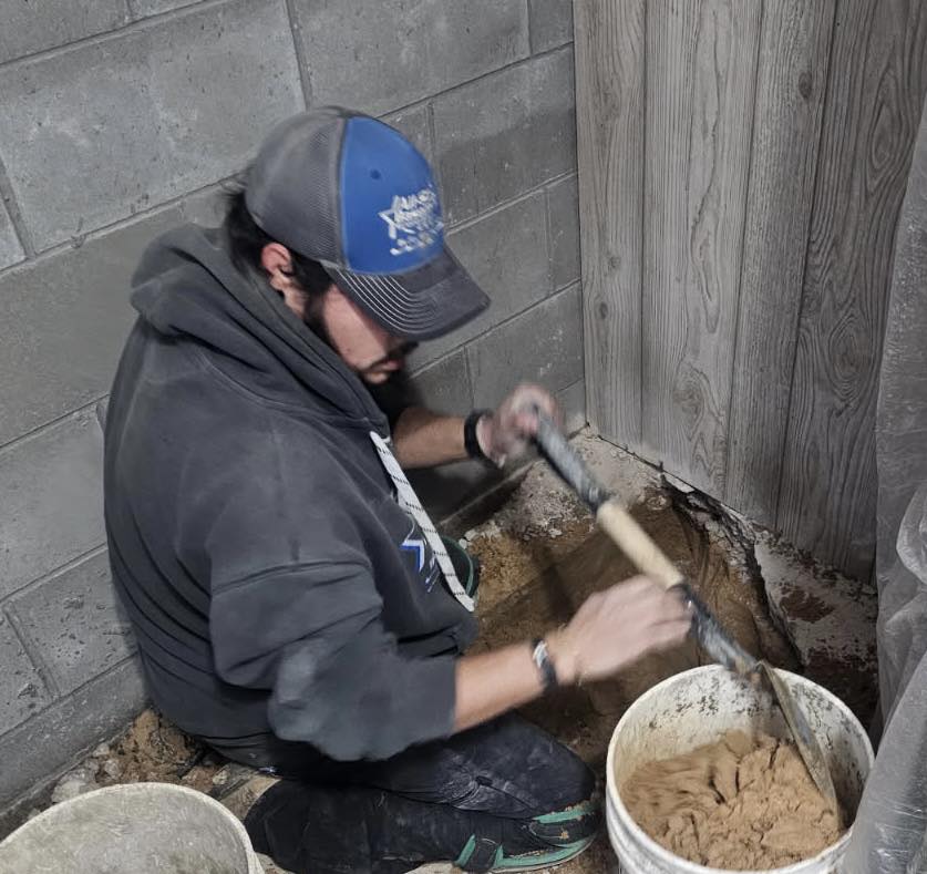 Technician installing a basement waterproofing solution near a foundation wall