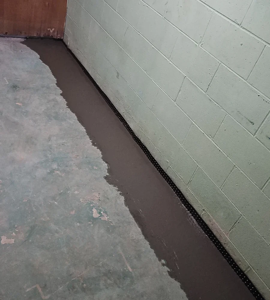 Freshly sealed interior drainage system installed along the basement perimeter during a basement waterproofing project in Dodge Center, MN.