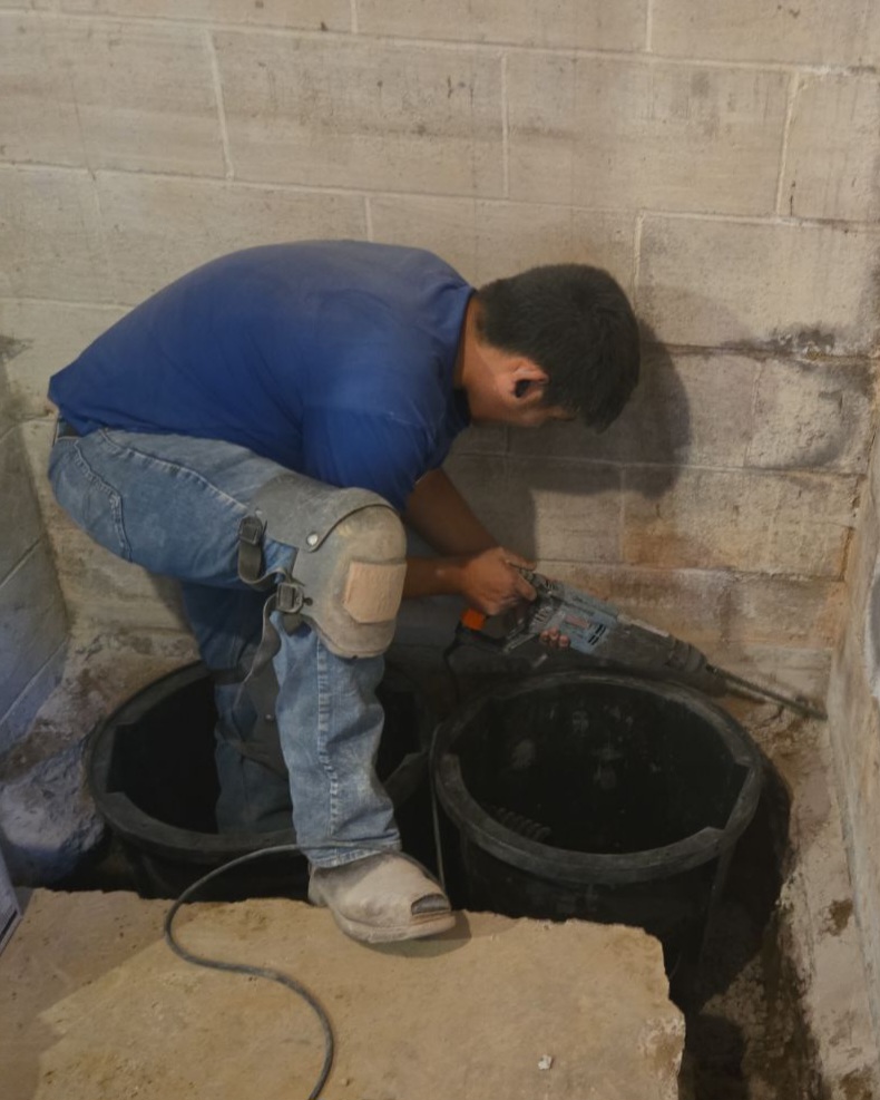 Technician installing a sump pump system for basement waterproofing in Eau Claire, WI